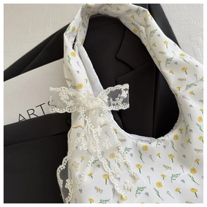 Close-up of floral canvas tote bag with bee print and decorative lace bow on side