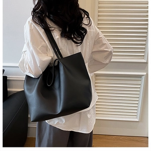Minimalist large black leather tote bag shown on shoulder for daily commute style