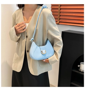 Detail of light blue crescent shoulder bag with golden D-clasp and knotted strap