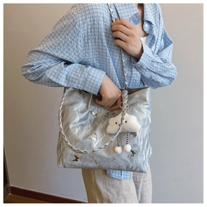 Detail of silver metallic tote bag with gold butterfly accents and cloud charm