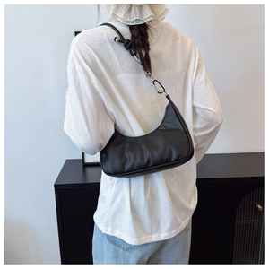 Detail showing the black hobo shoulder bag with a unique knotted strap and metal ball decor