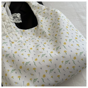 Detail of floral tote bag with daisy pattern, green leaves and white lace ribbon bow