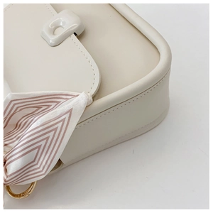 Close-up of cream white flap bag showing fine stitching and decorative silk scarf detail