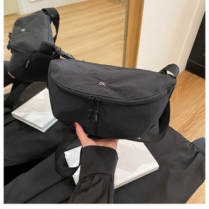 Close-up of black nylon crescent bag with OK logo and adjustable shoulder strap