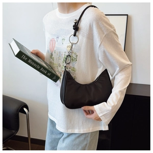 Side view of black hobo bag featuring decorative metal rings and leather knots on the strap