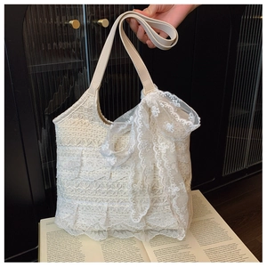 Detail of a cream lace tote bag featuring elegant lace trim and a large side bow design