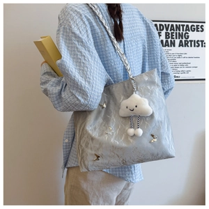 Detail of silver tote bag with metallic butterfly charms and plush cloud pendant