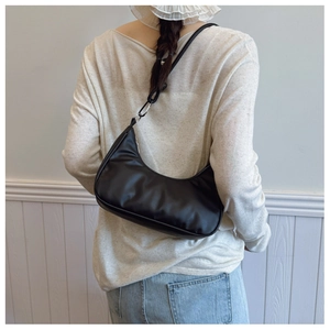 Close-up of a black crescent shoulder bag with silver hardware worn by a model