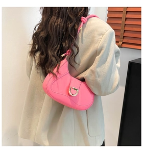 Detailed view of pink shoulder bag with gold D-shaped buckle worn by model