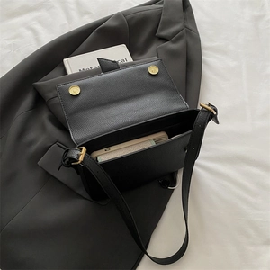 Minimalist black pebble leather baguette bag with dual gold magnetic clasps for women