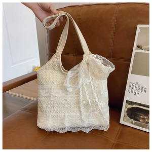 Detail of a beige lace tote bag featuring a decorative bow on the leather handle