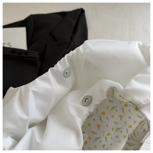 Detail of magnetic silver clasp and yellow floral lining on a white puffy canvas tote bag