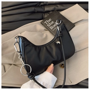 Detail of black crescent shoulder bag with silver hardware and knotted strap accents