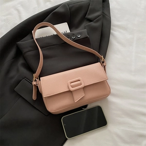 Dusty pink lychee texture leather baguette bag with retro gold hardware on black suit