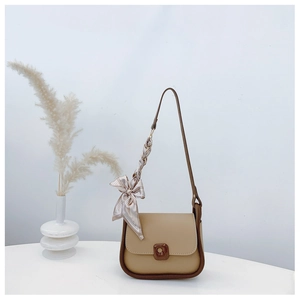 Detail of minimalist beige shoulder bag with brown trim and elegant silk scarf on strap