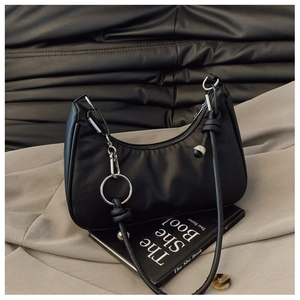 Close-up of black hobo bag detail with metal ring and silver ball charms on leather