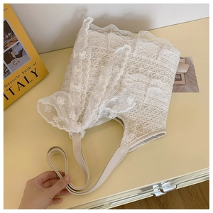 Close-up of white floral lace embroidery and beige leather straps on beach tote bag