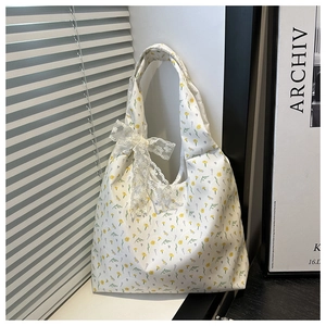 Detailed shot of floral canvas tote bag featuring a decorative lace bow and yellow flowers