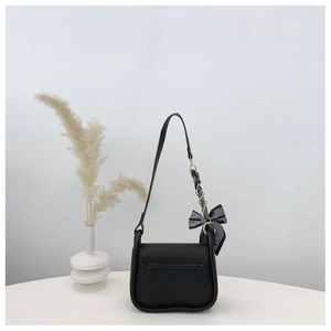 Close-up of black crossbody bag with gold chain strap and elegant silk ribbon detail