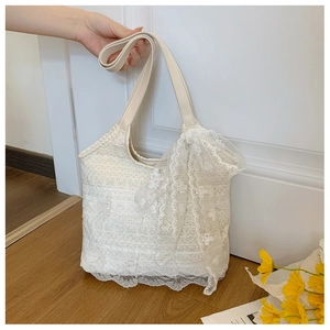 Close-up of white floral lace tote bag with delicate embroidery and large side bow detail