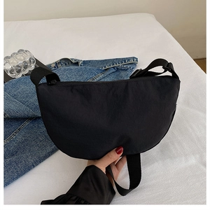 Close-up of lightweight black crescent crossbody bag with adjustable wide fabric strap