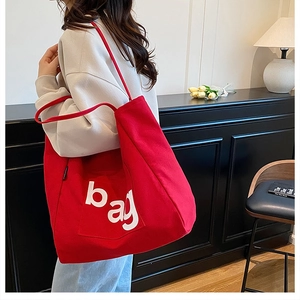 Close-up of red large canvas tote bag featuring white printed BAG letter design