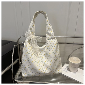 Floral canvas tote bag featuring delicate yellow flowers and lace bow detail on the strap