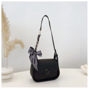 Detail of black leather crossbody bag with striped silk scarf ribbon on shoulder strap