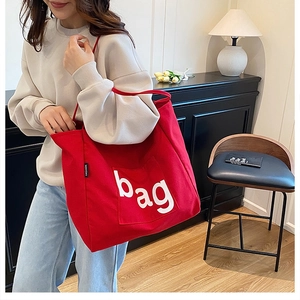 Close-up of a large red canvas tote bag with a white bag logo and fashion label detail