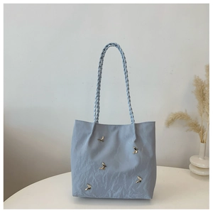 Detail of light blue crinkle texture tote bag with metallic butterfly accents and woven handle