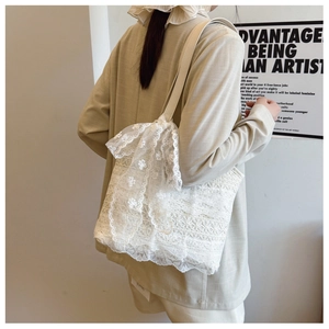 Close-up of white floral lace tote bag with large bow and cream leather shoulder strap