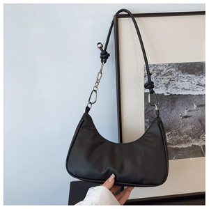 Detail of black hobo bag featuring metal chain and leather knot on the shoulder strap