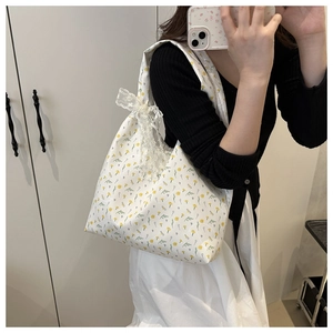 Detail of floral canvas tote bag with white lace bow and delicate yellow flower patterns