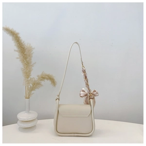 Detail of a beige leather shoulder bag featuring an elegant striped silk scarf bow