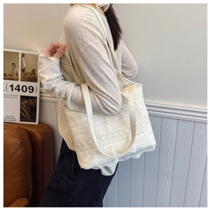 Detail of floral lace embroidery on cream white tote bag with leather straps