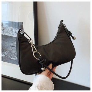 Detail of black crescent hobo bag featuring silver chain and knotted metal ball pendant