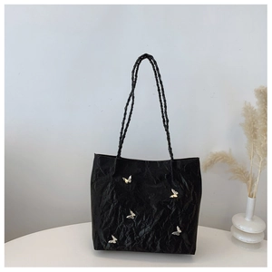 Detail of black pleated tote bag featuring decorative silver butterfly accents and woven strap
