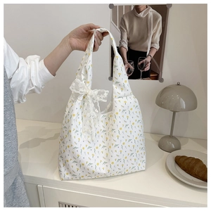 Floral canvas tote bag featuring a white lace bow detail and dainty yellow flower patterns