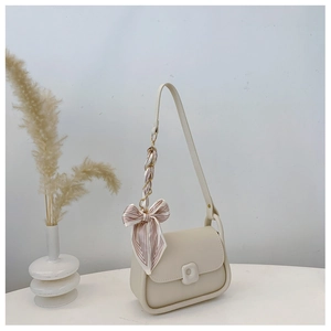 Detail of cream leather saddle bag with square buckle and pink silk scarf bow accent