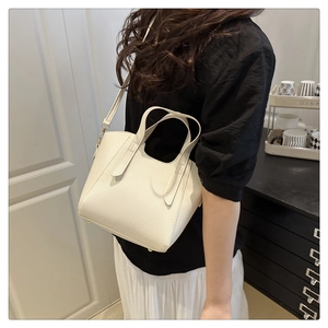 Dettaglio borsa beige con trama litchi, piedini in metallo e tracolla regolabile