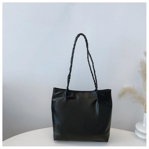 Detail of minimalist black tote bag with long braided straps on a clean white surface