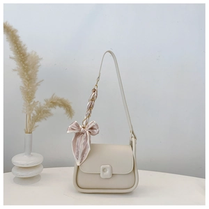 Detail of beige faux leather saddle bag featuring silk scarf handle and retro metal buckle