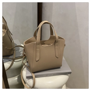 Dettaglio della texture in pelle martellata sulla borsa a secchiello beige minimalista