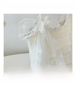 Detail einer weißen Spitzentasche mit floraler Stickerei und einer mehrlagigen Schleife