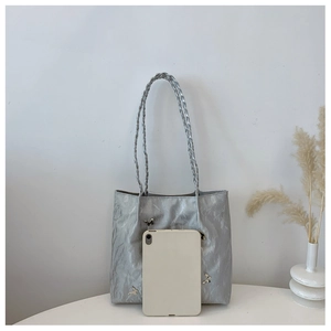 Silver tote bag with metal butterfly details next to a tablet for size reference
