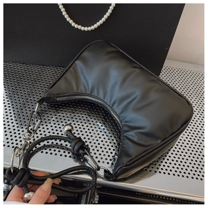 Detail of black half-moon hobo bag with silver ball charms and knot strap design
