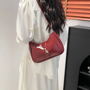 Borsa sottobraccio in finta pelle bordeaux lucida con fibbia dorata su abito bianco