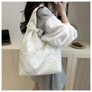 Close-up of floral canvas tote bag featuring yellow flower patterns and lace bow detail