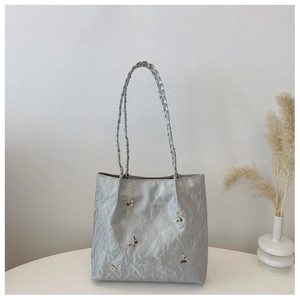 Close-up of silver tote bag with metallic butterfly accents and woven strap detail