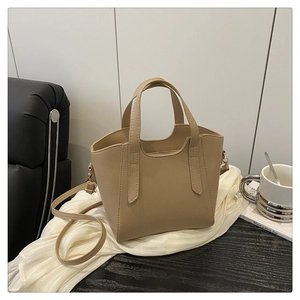 Dettaglio borsa a secchiello beige con trama litchi e doppi manici su seta bianca